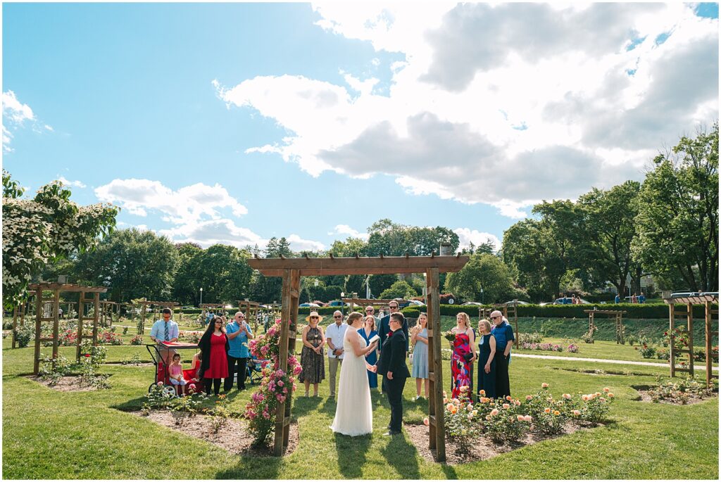 Guests watch a wedding ceremony on a sunny day at the Malcolm Gross Rose Garden.