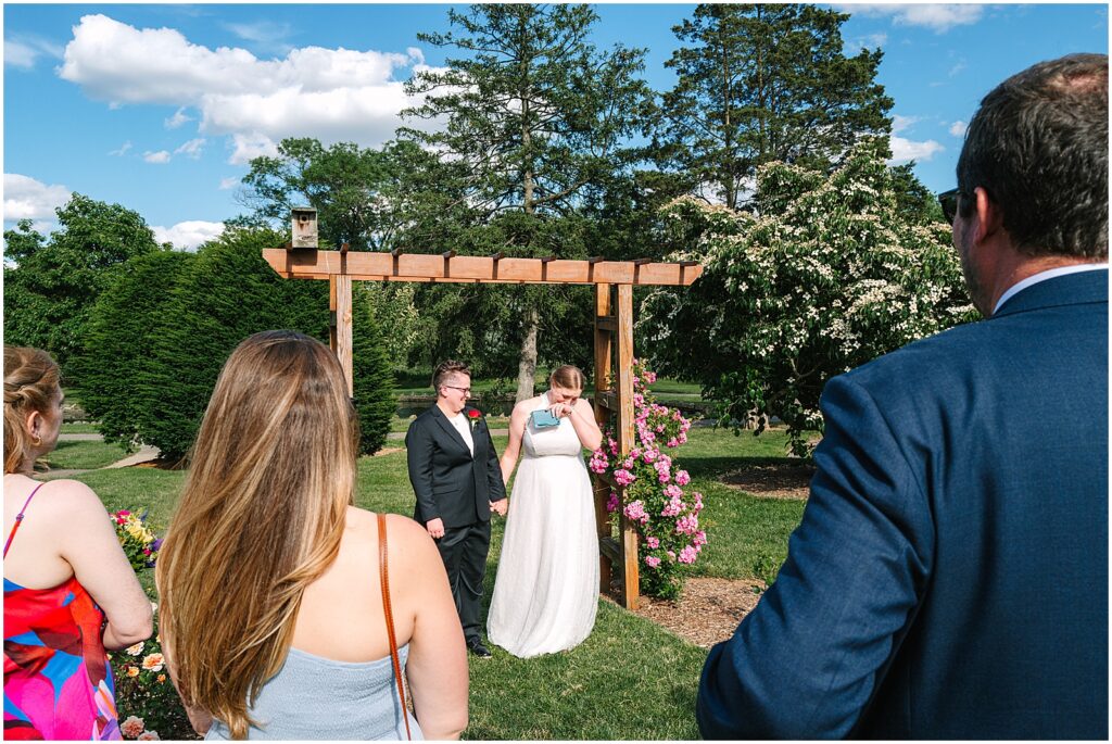 Two brides turn to face their wedding guests at the end of their garden wedding ceremony.