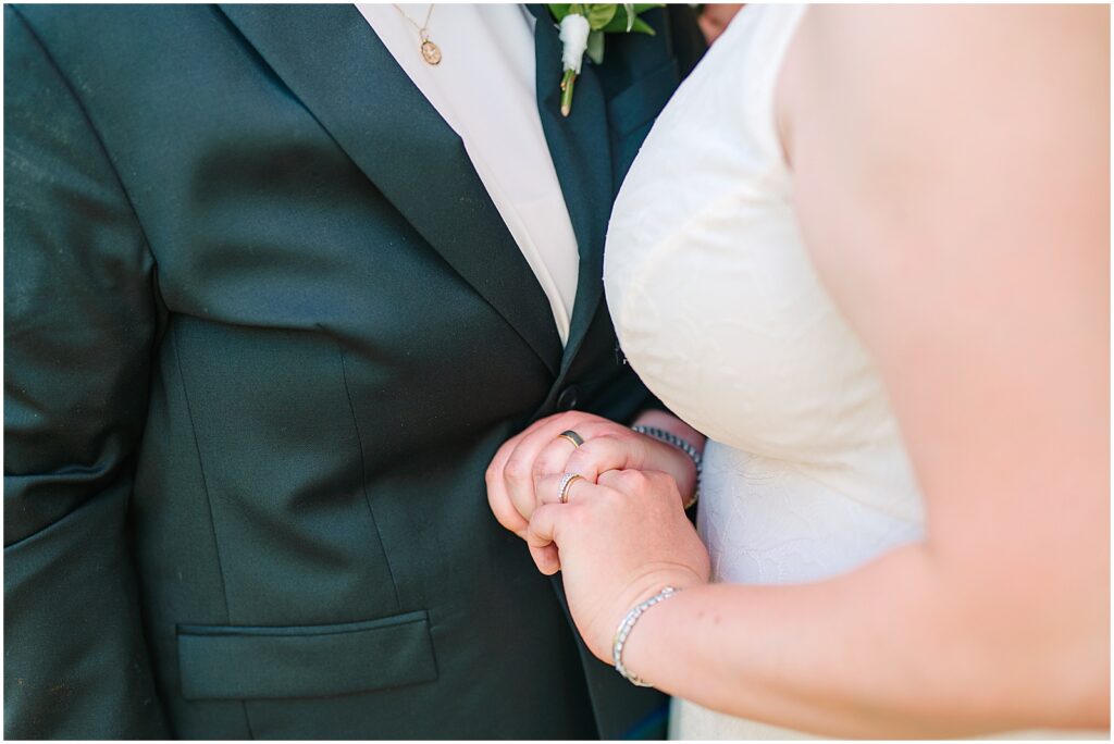 Two marriers hold hands showing their wedding rings to a Philadelphia wedding photographer.