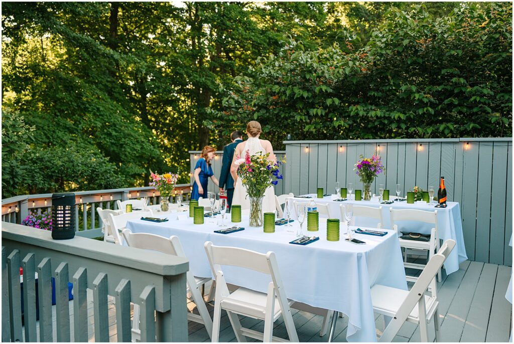 People walk off a deck decorated for a backyard wedding reception.