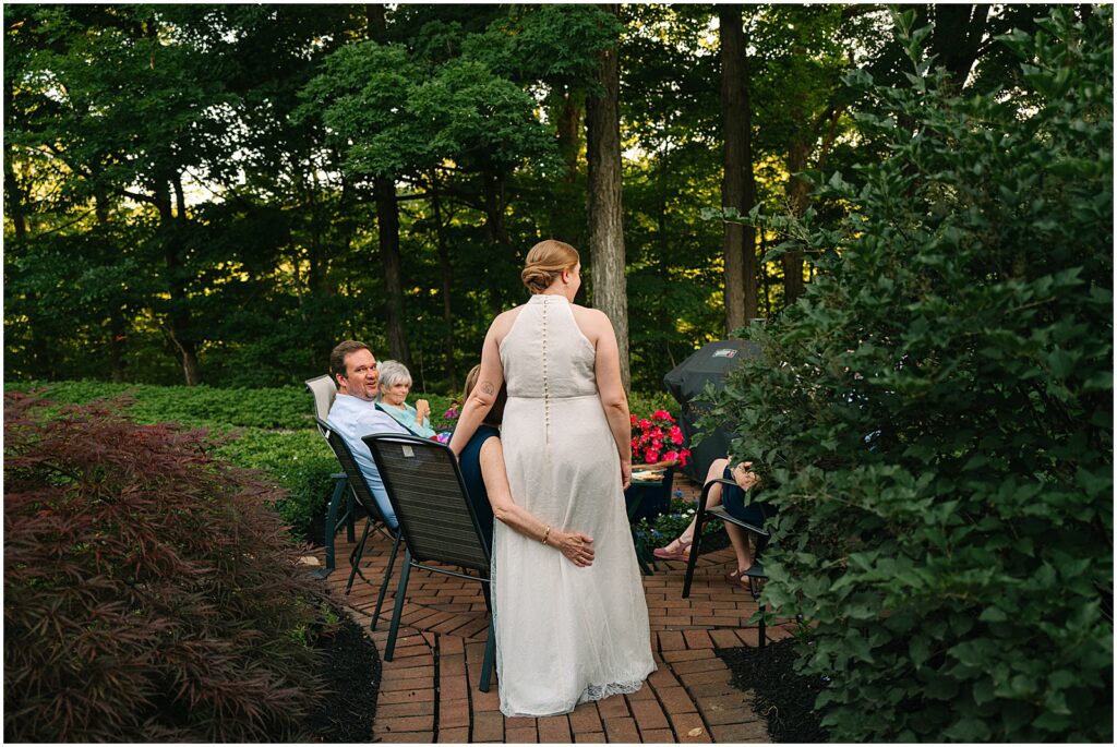 A bride leans against a family member seated by a fire pit.