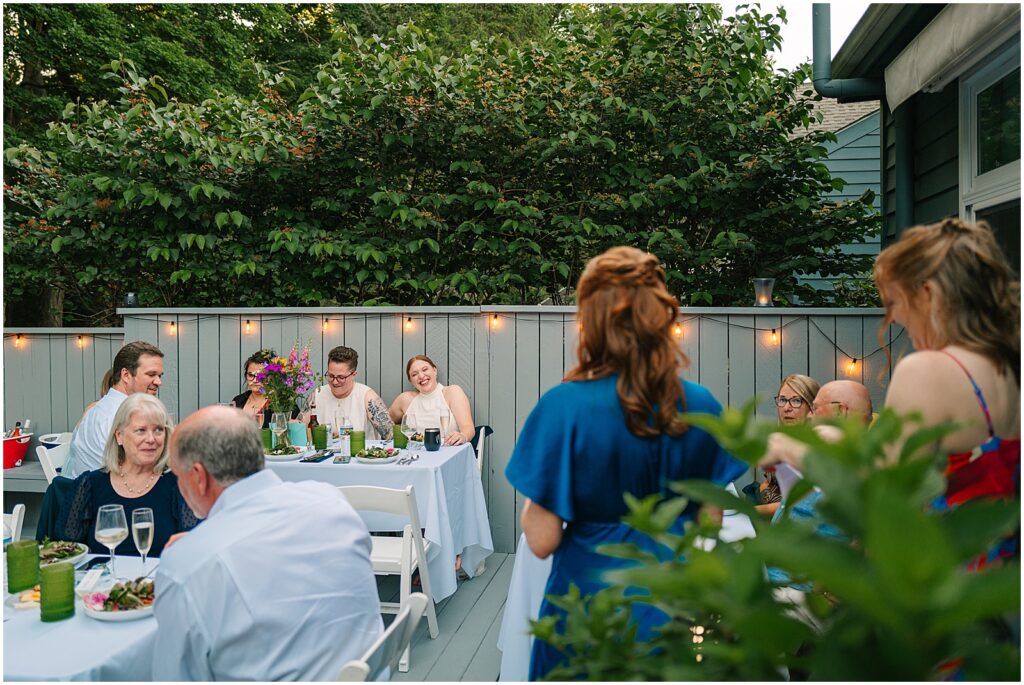 Brides and their guests listen to a toast given by friends.