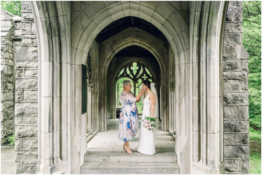 A bride's mother puts her hands on her cheeks.