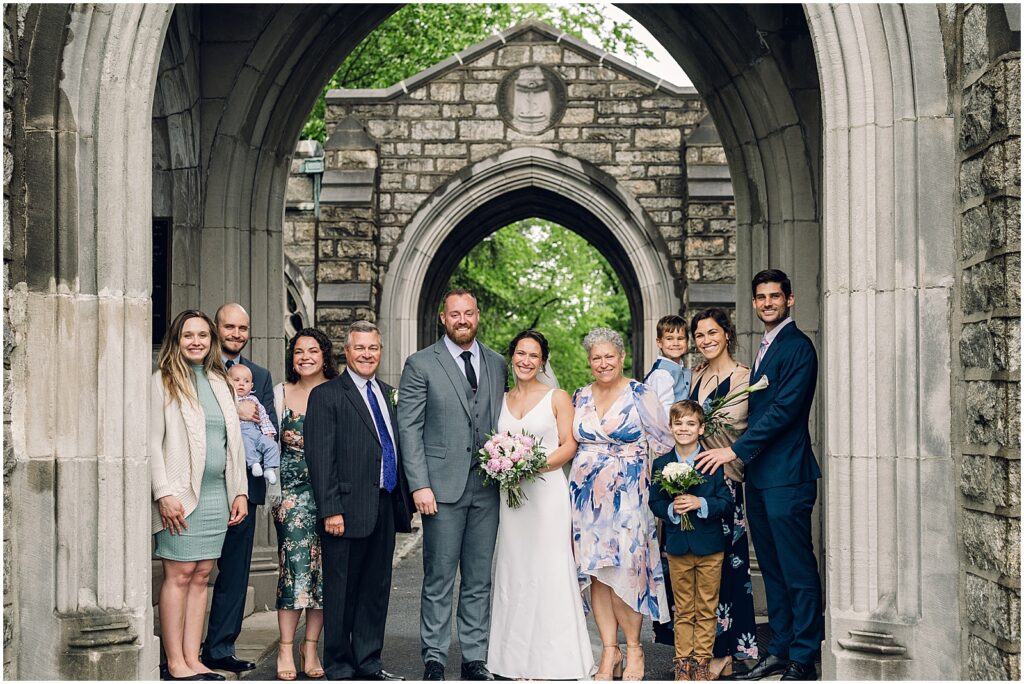 A bride and groom pose with family members for a formal portrait.