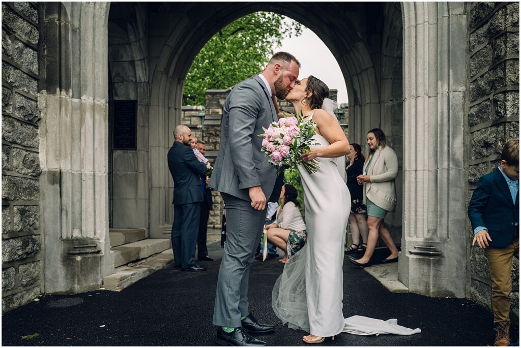 A bride and groom kiss in a candid wedding photo.