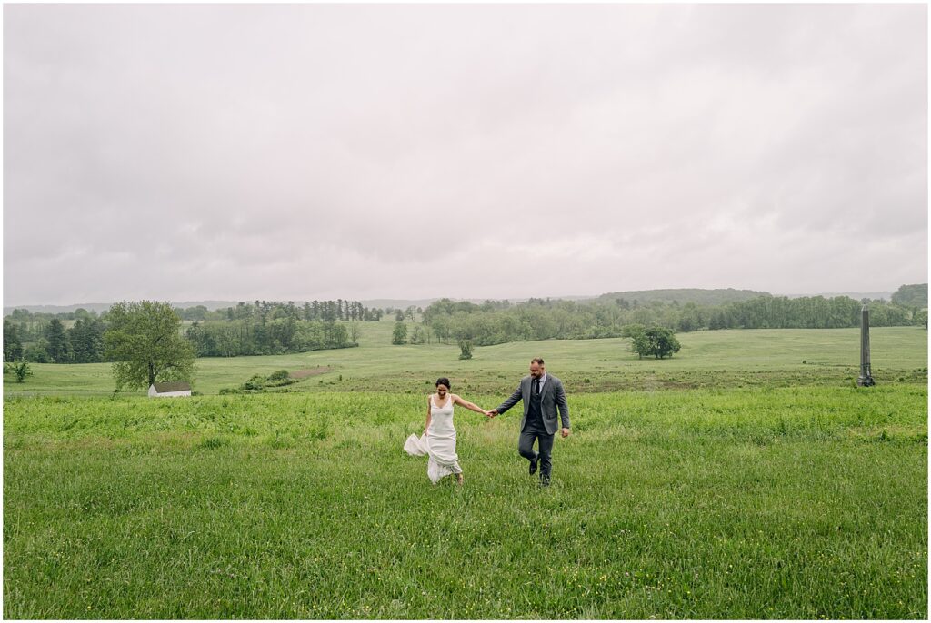 A bride and groom run through a rainy Pennsylvania field.