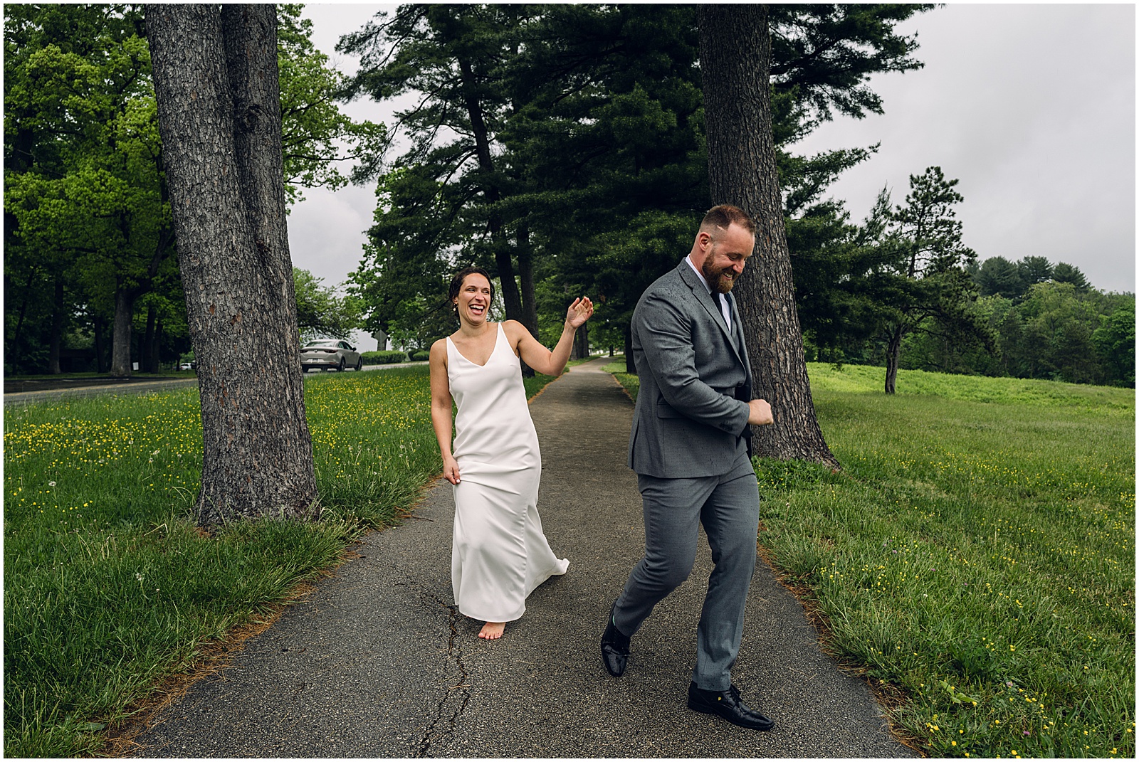 A bride and groom run laughing through the rain in a candid wedding photo.