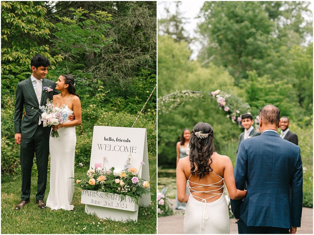 A bride and groom stand beside a welcome sign at their summer wedding.