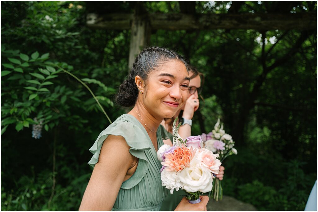 A bridesmaid in a green dress smiles at a Philadelphia wedding photographer.