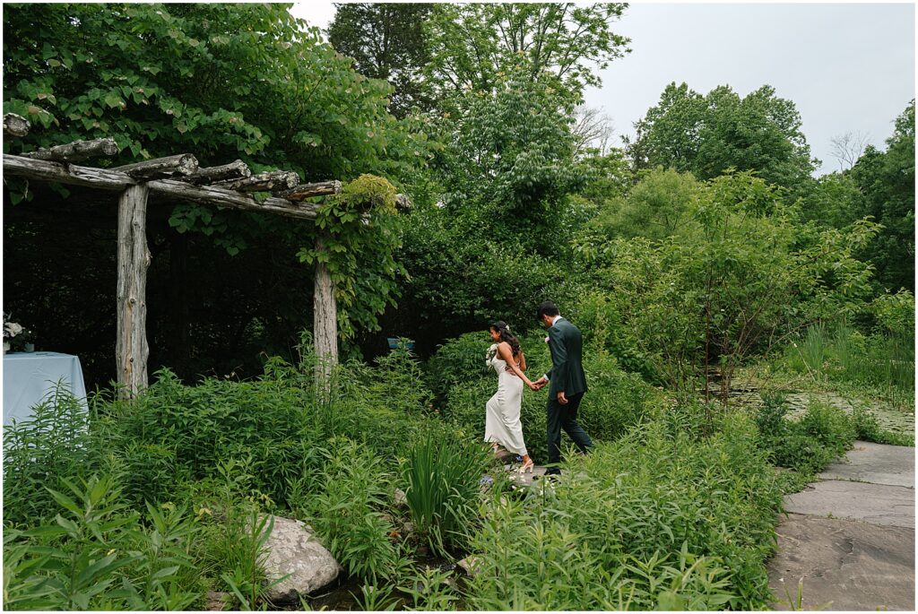 A bride leads a groom through a lush garden at Bowman's Hill Wildflower Preserve.