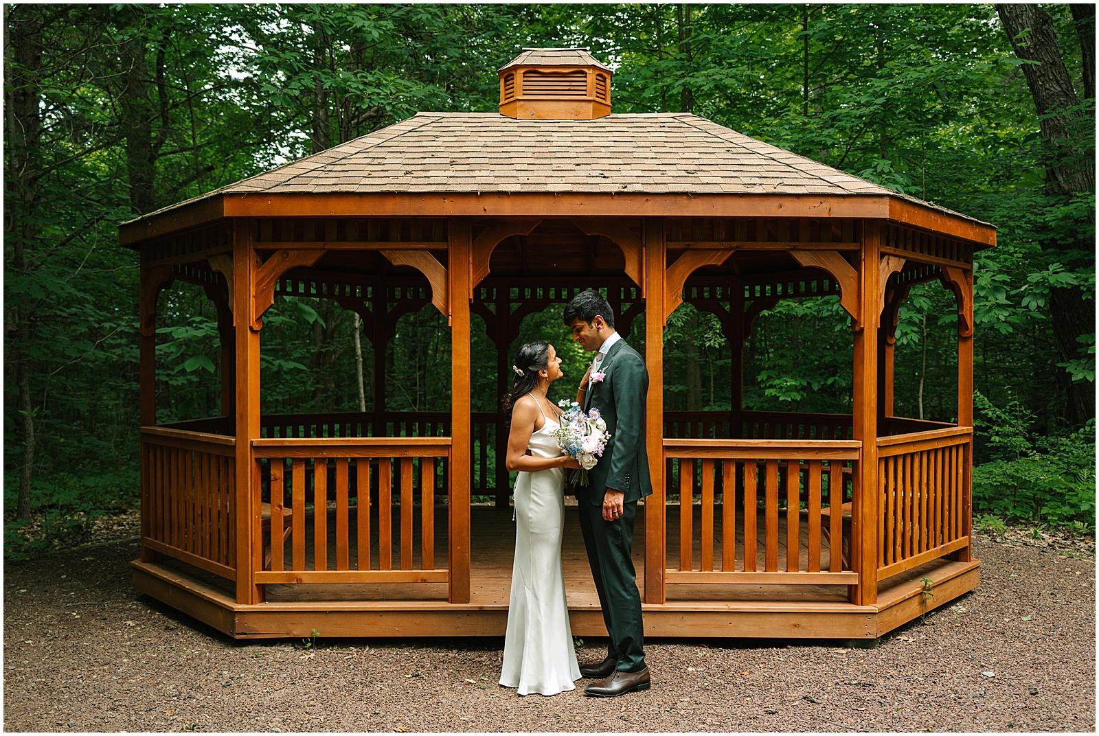 A bride and groom stand in front of a gazebo in Bowman's Hill Wildflower Preserve.