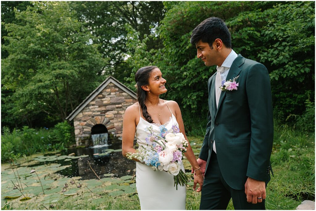 A bride and groom hold hands beside a pond at Bowman's Hill Wildflower Preserve