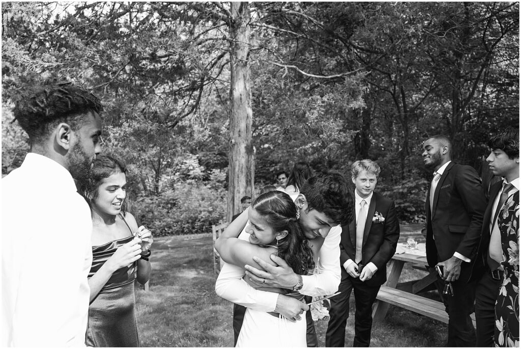 A bride hugs a groom during an outdoor wedding reception.