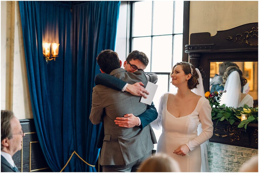 A groom hugs a friend.