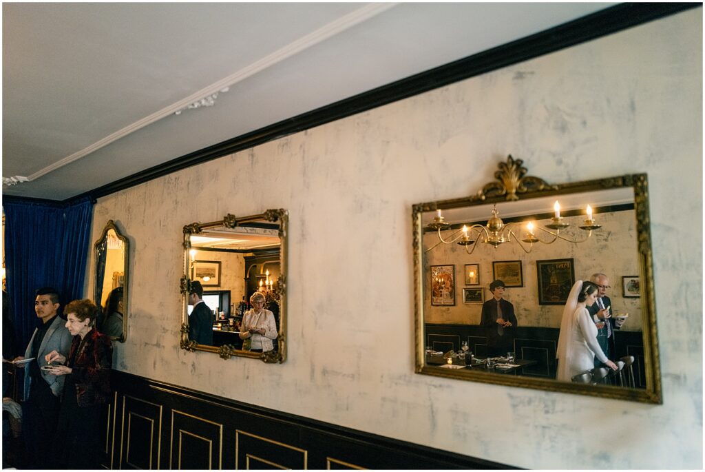 Mirrors reflect a bride talking to wedding guests in a private dining room.