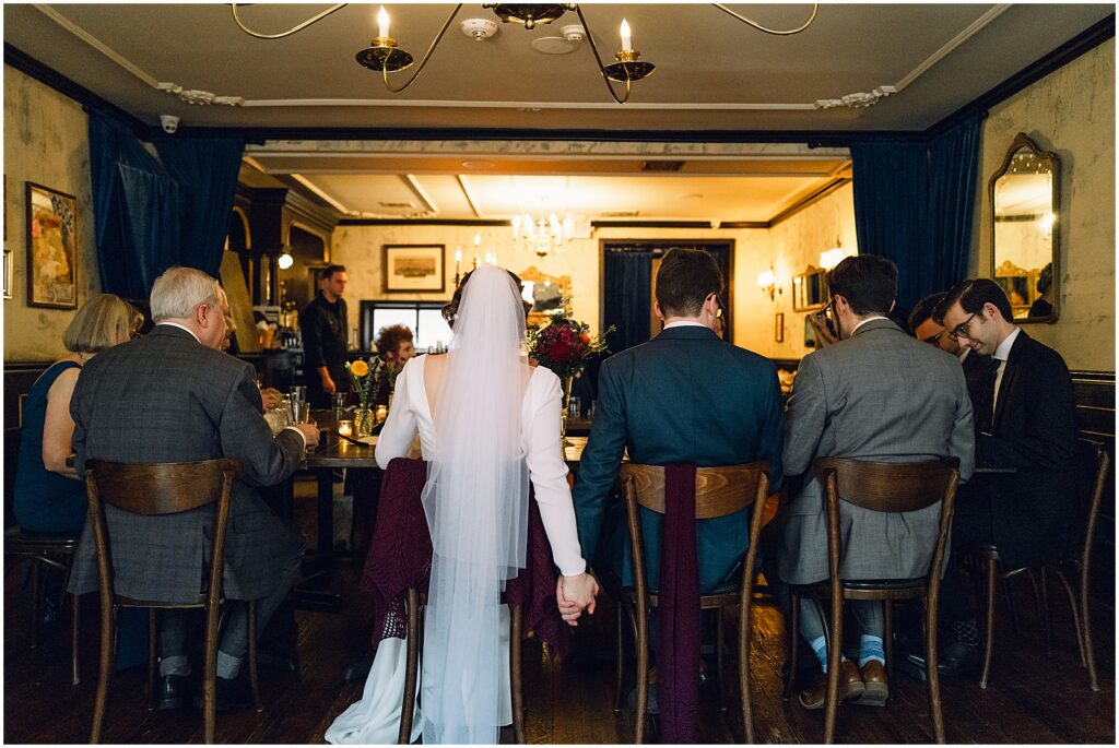 A bride and groom hold hands at a dining table inside Royal Boucherie.