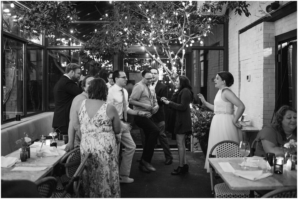 A bride dances with friends on a patio.