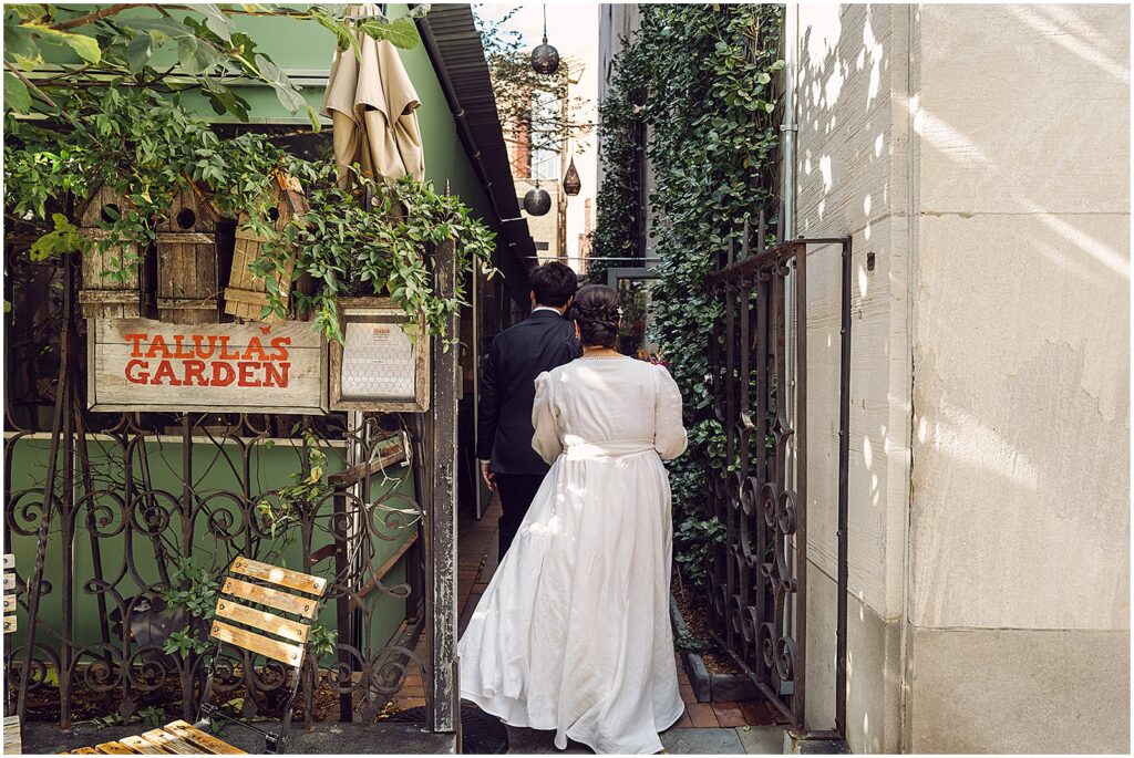 A bride and groom walk through the gate to Talula's Garden.