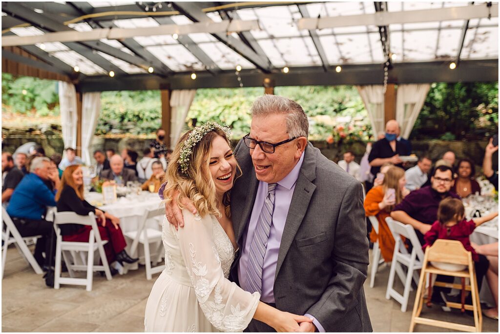 A bride dances with her father on a covered patio.