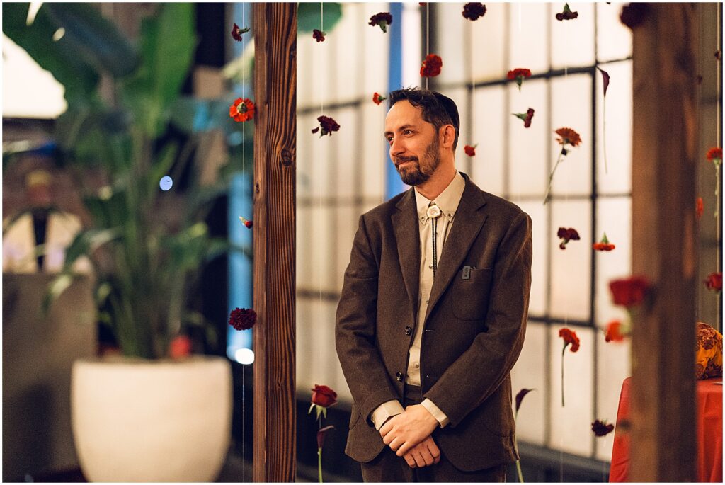A groom smiles as a bride walks towards him at a Lilah Philadelphia wedding ceremony.