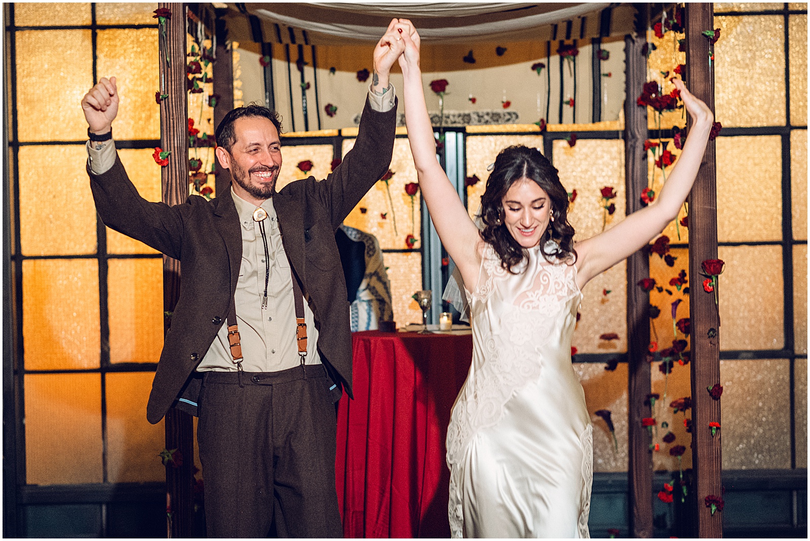 A bride and groom raise their hands at the end of their Jewish wedding ceremony in Fishtown.