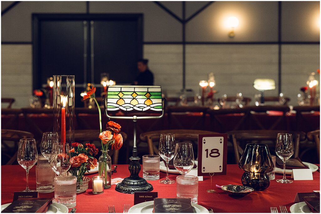 Vintage lamps and candles light reception tables with red linens.