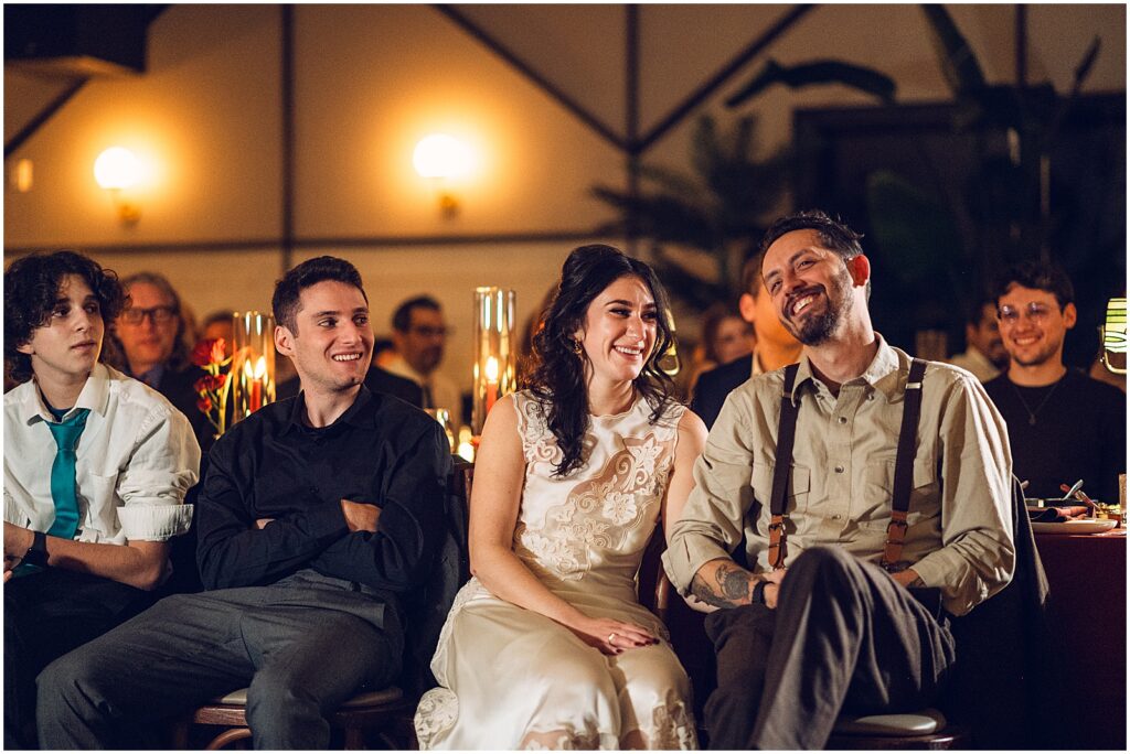A bride and groom hold hands while they listen to a speech at Lilah Philadelphia.