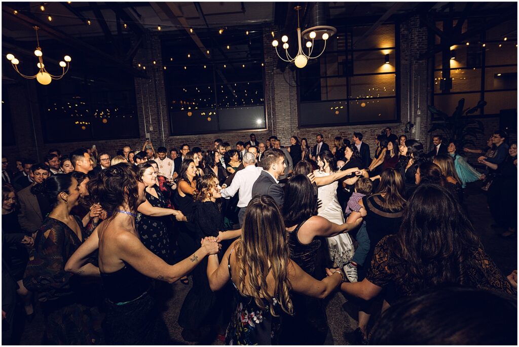 Wedding guests dance in circles around a bride and groom.