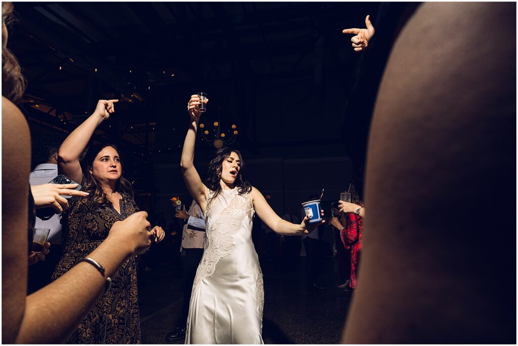 A bride dances with her arm raised.