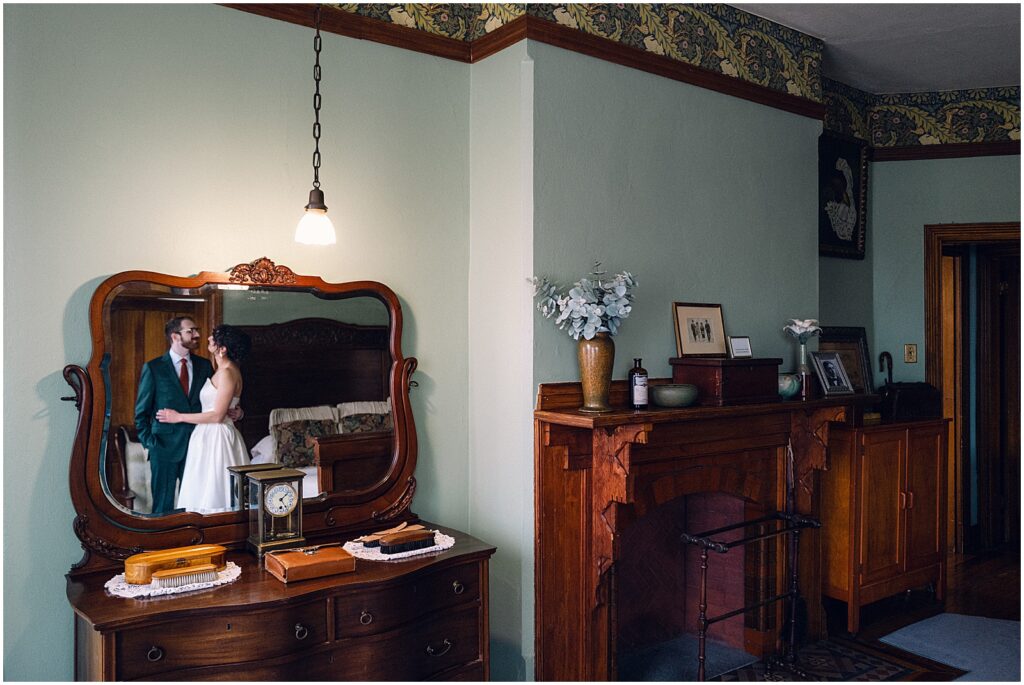 A mirror reflects a bride and groom getting ready together in a historic wedding venue.