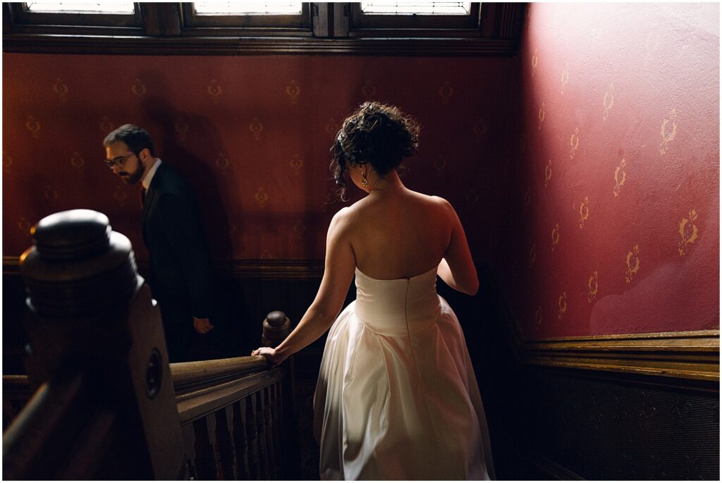 A bride and groom walk down a dark staircase at a Philly wedding venue.