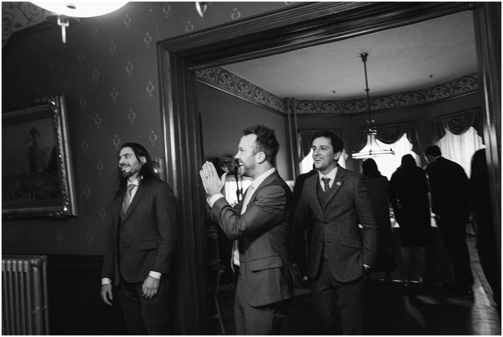 Wedding guests stand around a room clapping.