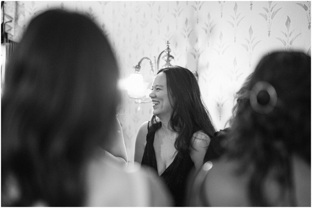 A wedding guest smiles as she talks with another guest.
