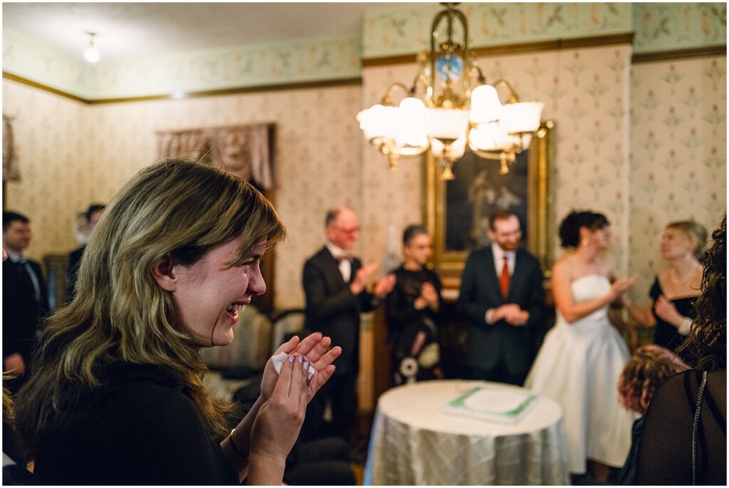 A bride and guests stand while they listen to a speech.