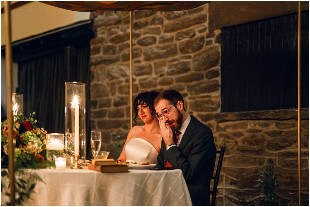 A groom wipes away a tear during a wedding toast.