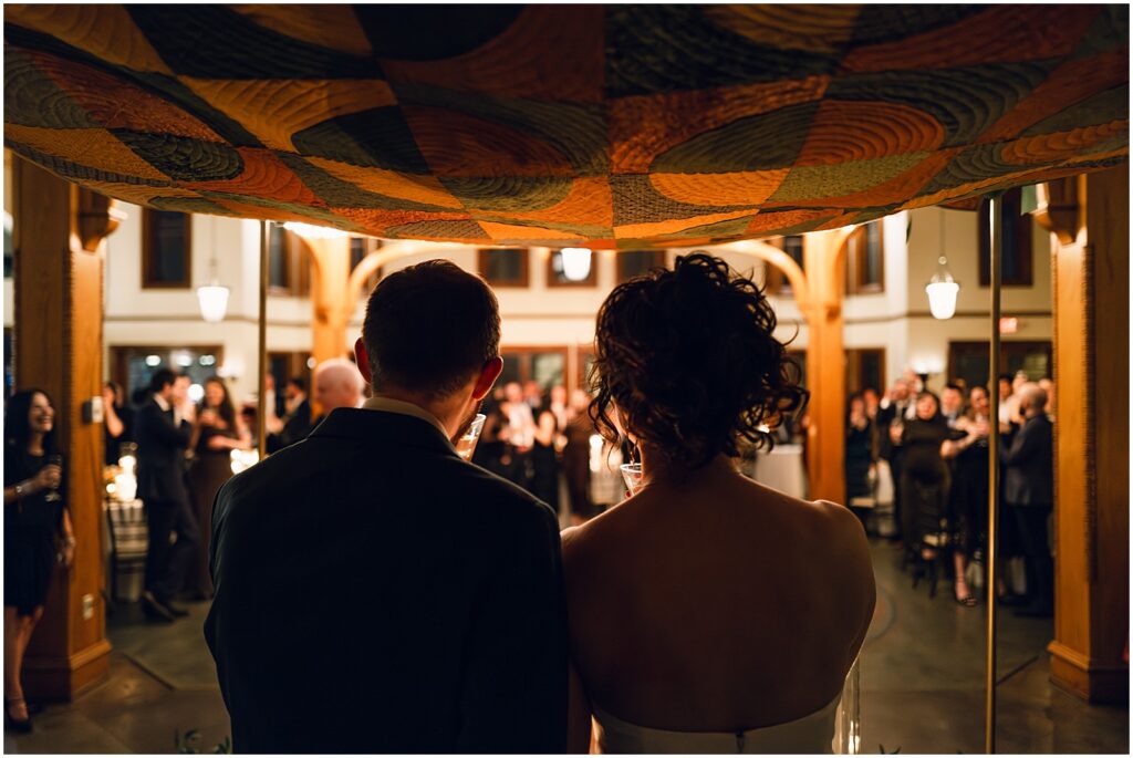 A bride and groom sit beneath a chuppah at their wedding reception.