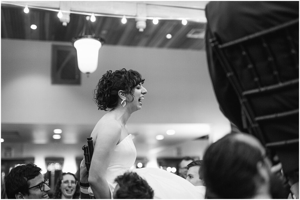A bride laughs as she's lifted for the hora.