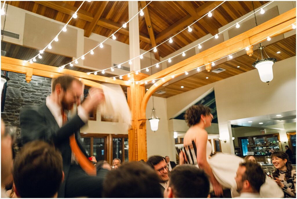 Guests pick up a bride and groom in chairs for the hora.