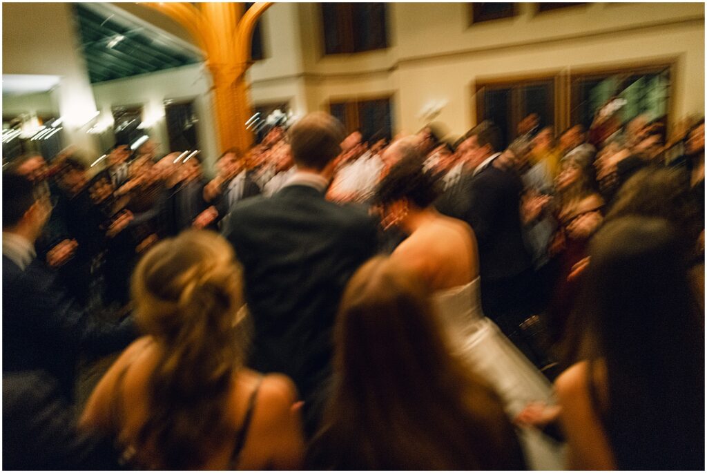 A bride and groom dance surrounded by guests.