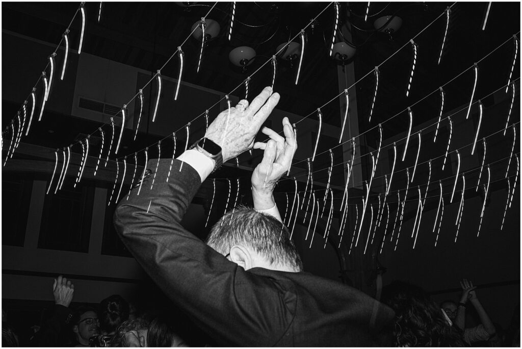 A wedding guest raises his hands in the air.