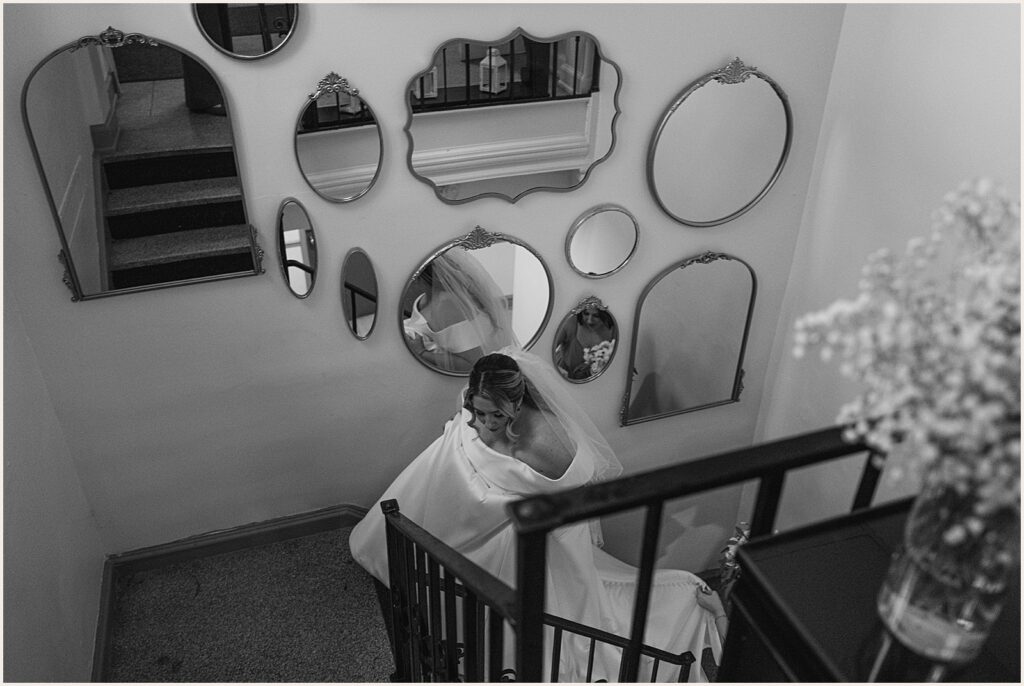 A bride walks up a staircase lined with mirrors inside Curtis Hall.