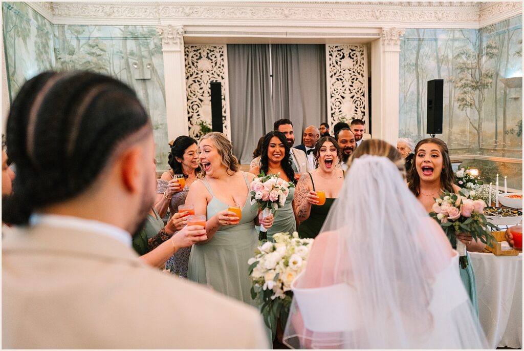 A group of bridesmaids reacts to a bride's entrance.
