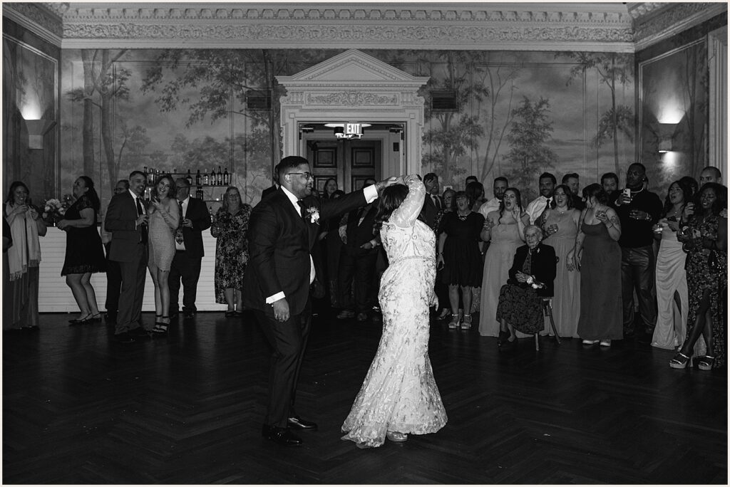 A groom twirls his mother during the mother-son dance at a wedding.
