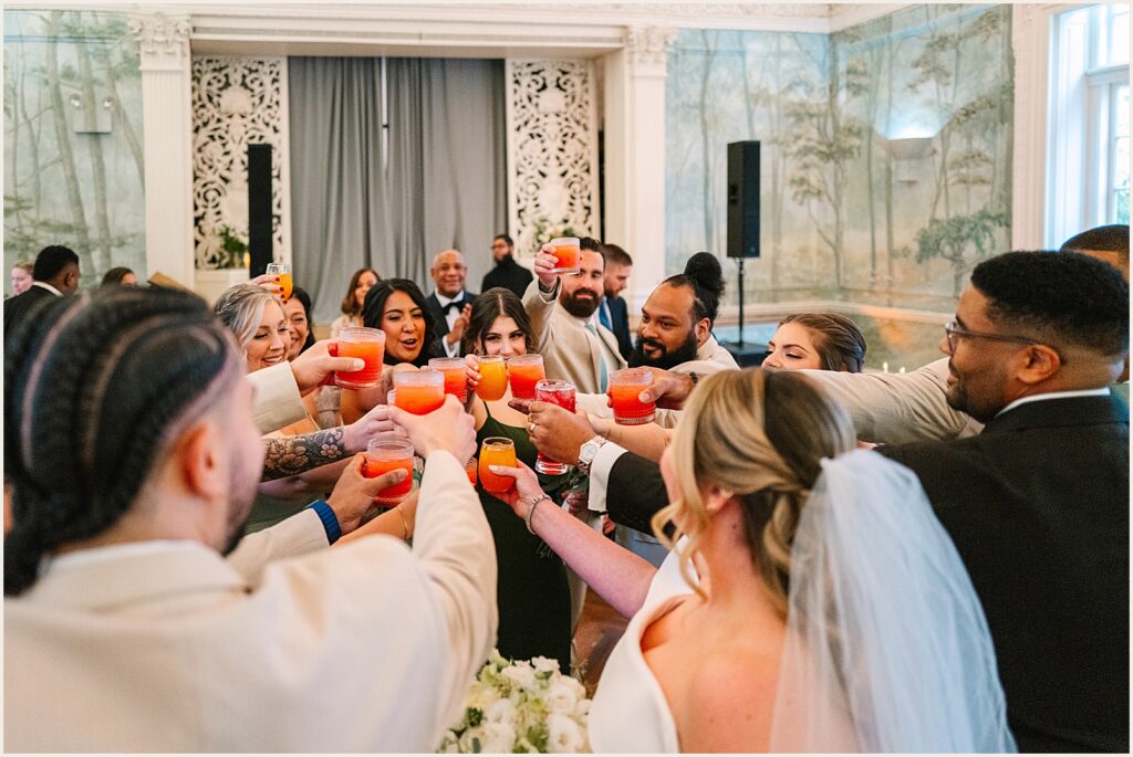 Wedding guests raise cocktails for a toast.