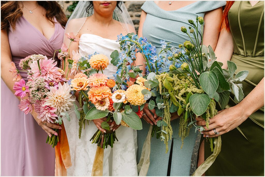 A bride and bridesmaids hold colorful bouquets that match their dresses.
