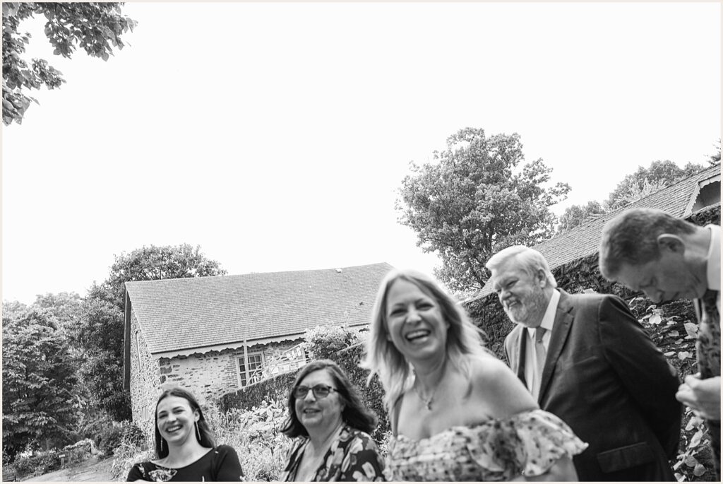 Wedding guests laugh as they walk towards a ceremony.