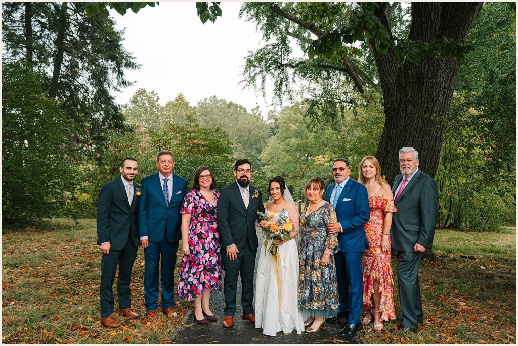 A bride and groom pose for a family portrait with their relatives.