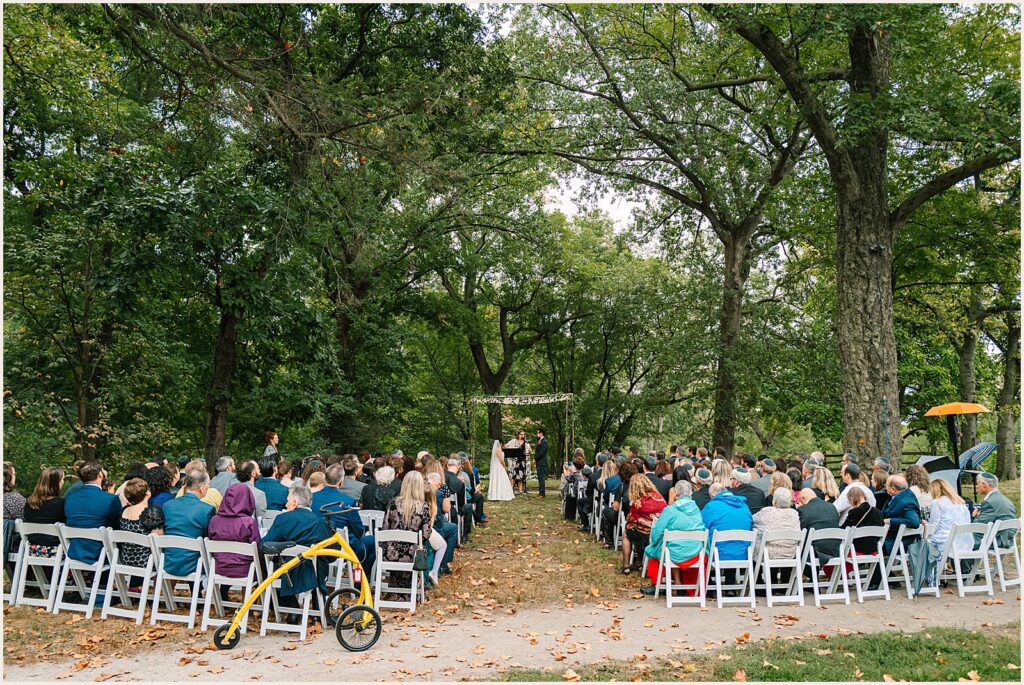 Wedding guests watch a Bartram's Garden wedding under a tree.