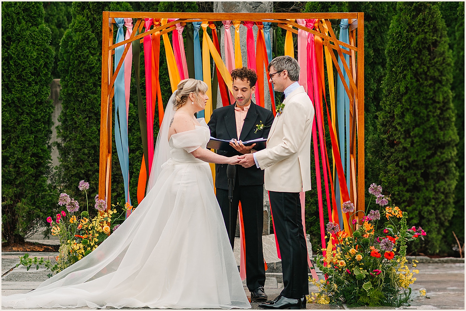 A bride and groom hold hands during a wedding ceremony at Grounds for Sculpture.