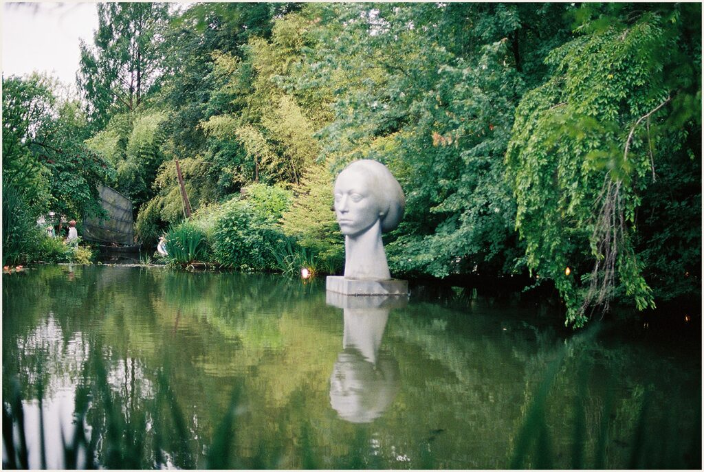 A large bust sits beside a lake at Grounds for Sculpture.